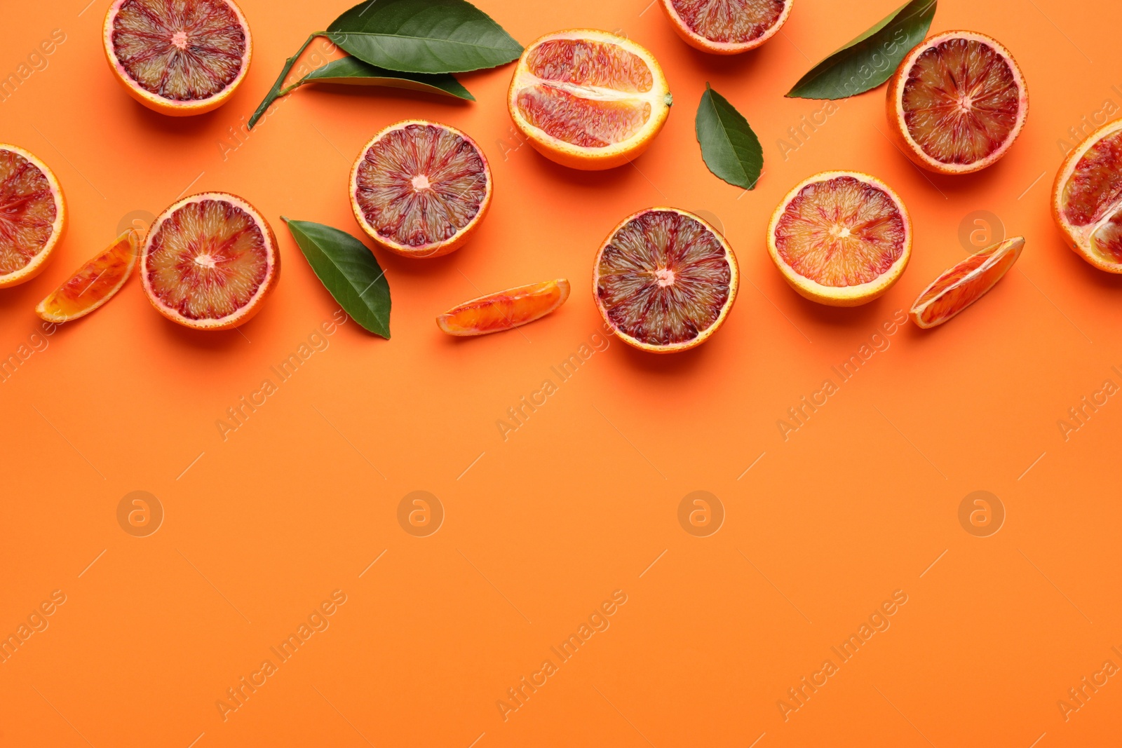 Photo of Many ripe sicilian oranges and leaves on orange background, flat lay. Space for text