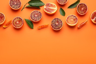 Photo of Many ripe sicilian oranges and leaves on orange background, flat lay. Space for text
