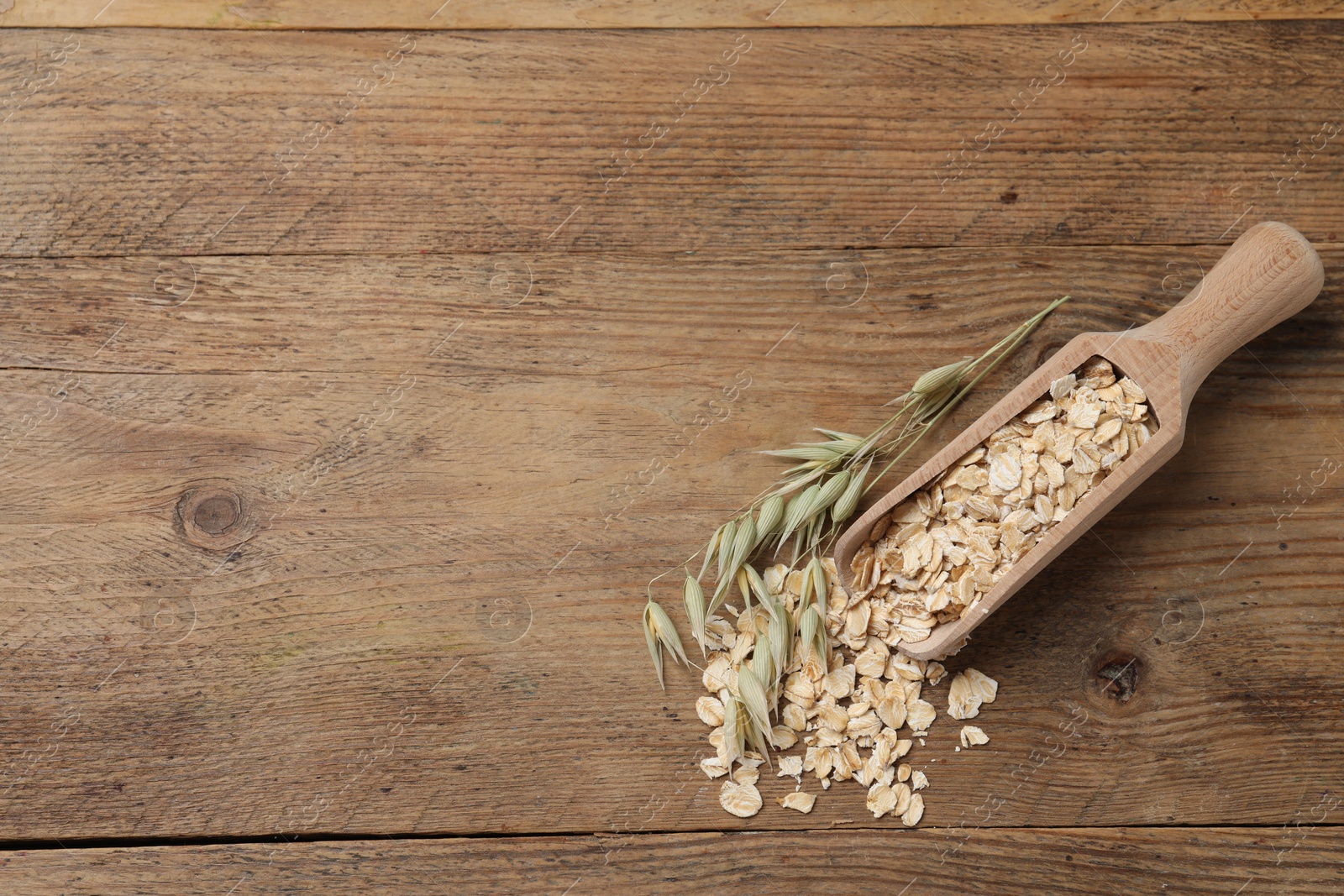 Photo of Scoop with oatmeal and floret branches on wooden table, top view. Space for text