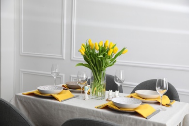 Photo of Beautiful Easter table setting with yellow tulips indoors