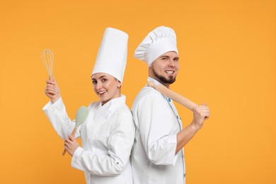 Photo of Happy confectioners in uniforms holding professional tools on yellow background