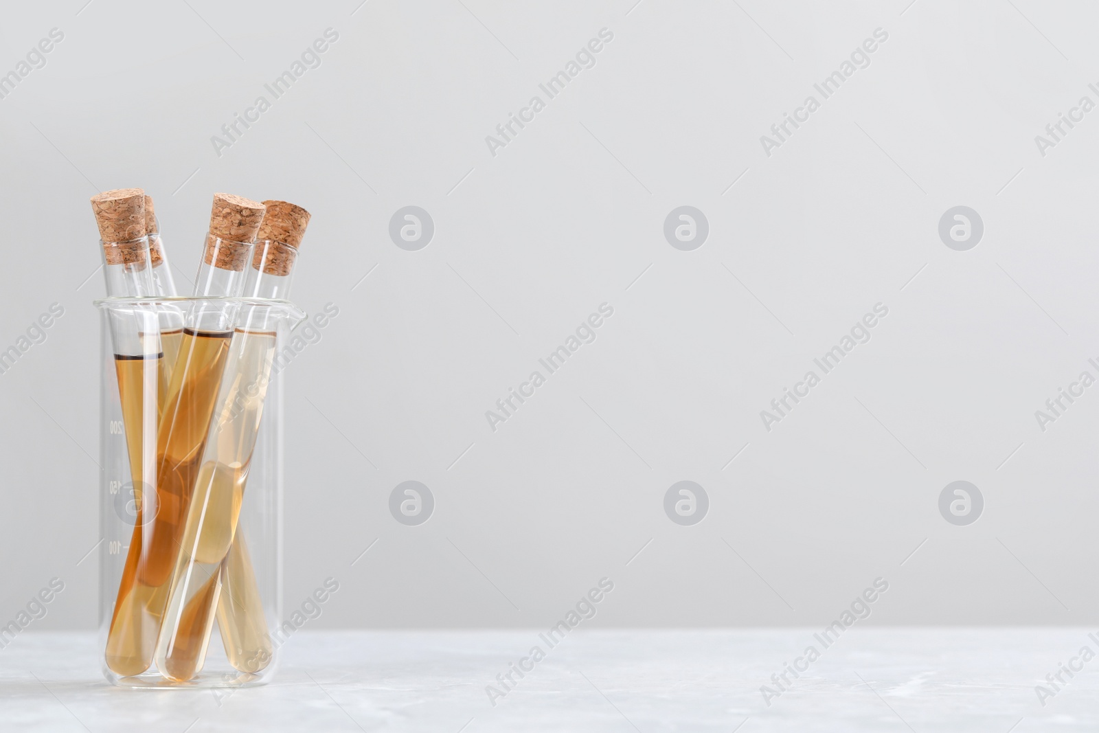 Photo of Test tubes with brown liquid on white table against light background. Space for text