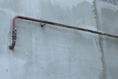 Photo of Rusty gas pipe at light wall outdoors, low angle view