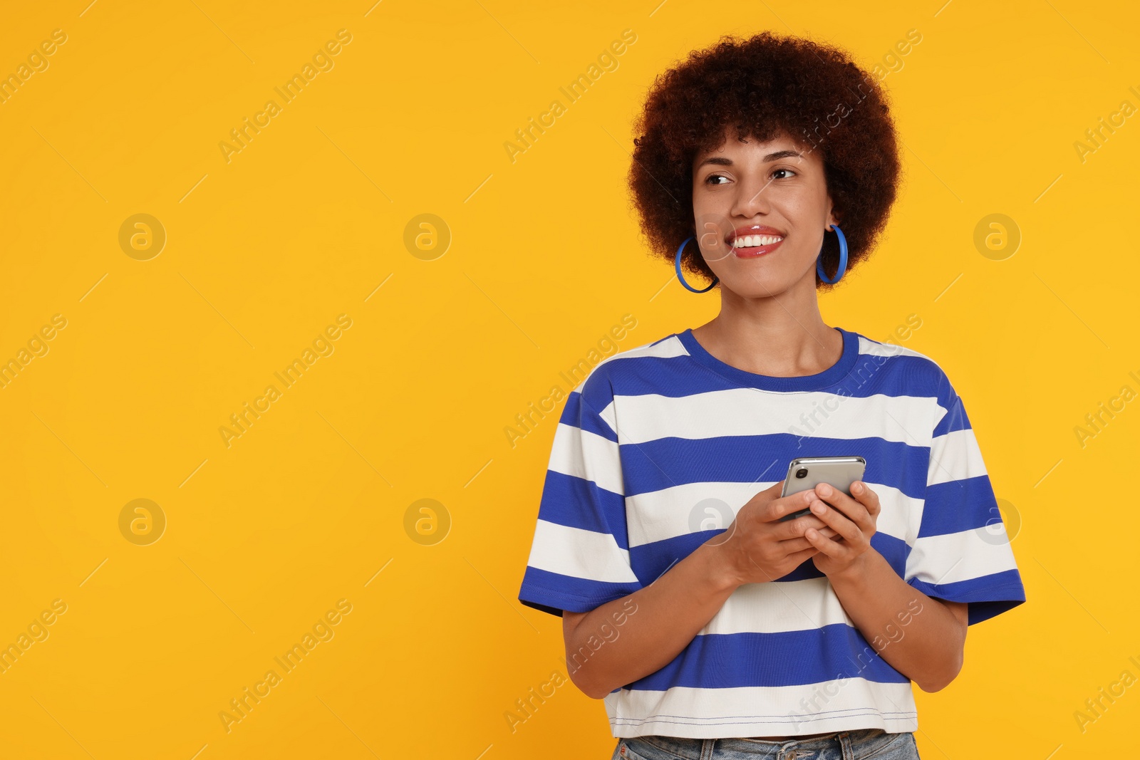 Photo of Happy young woman with smartphone on orange background. Space for text