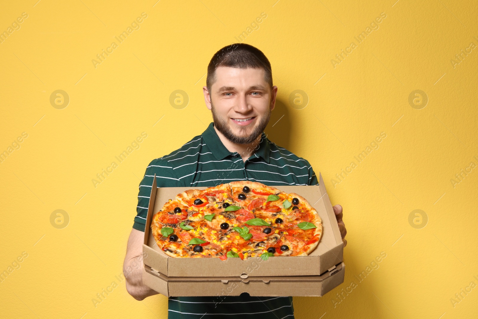 Photo of Attractive young man with delicious pizza on color background