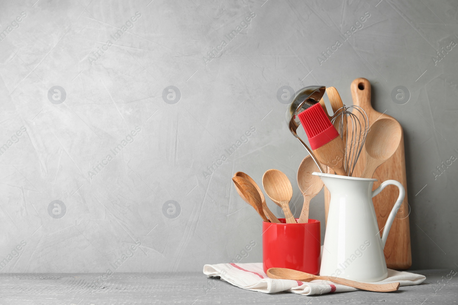 Photo of Different kitchen utensils on wooden table against light grey background. Space for text