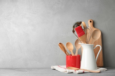 Different kitchen utensils on wooden table against light grey background. Space for text