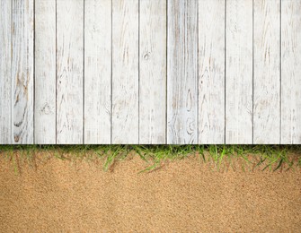 Image of Sand, green grass and white wooden planks outdoors, top view