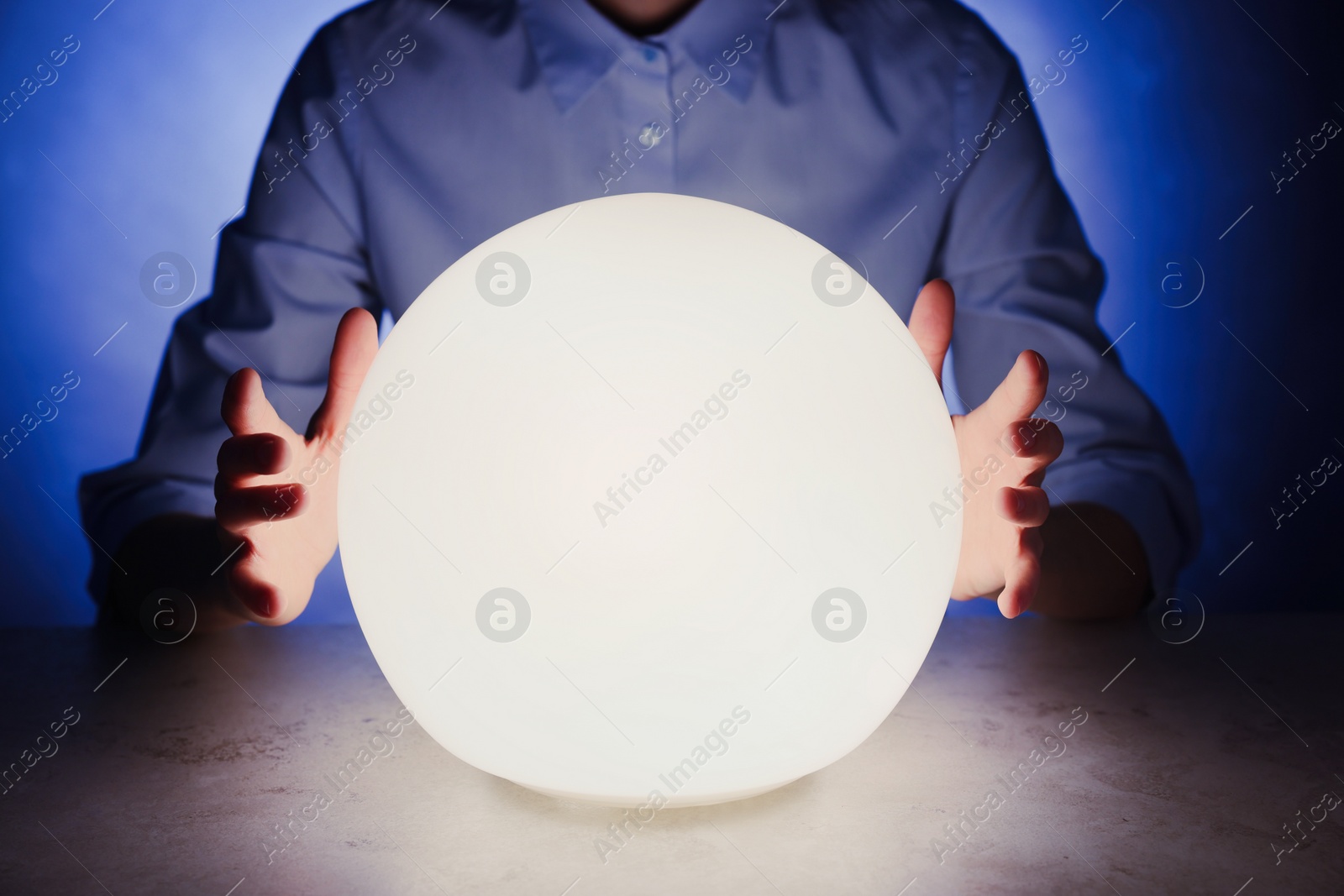 Photo of Businesswoman using glowing crystal ball to predict future at table in darkness, closeup. Fortune telling