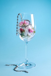 Elegant jewelry. Stylish presentation with luxury earrings, bracelets and frozen roses in glass on light blue background