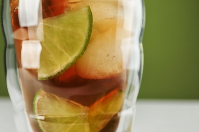 Photo of Glass of tasty ice tea with lime, closeup