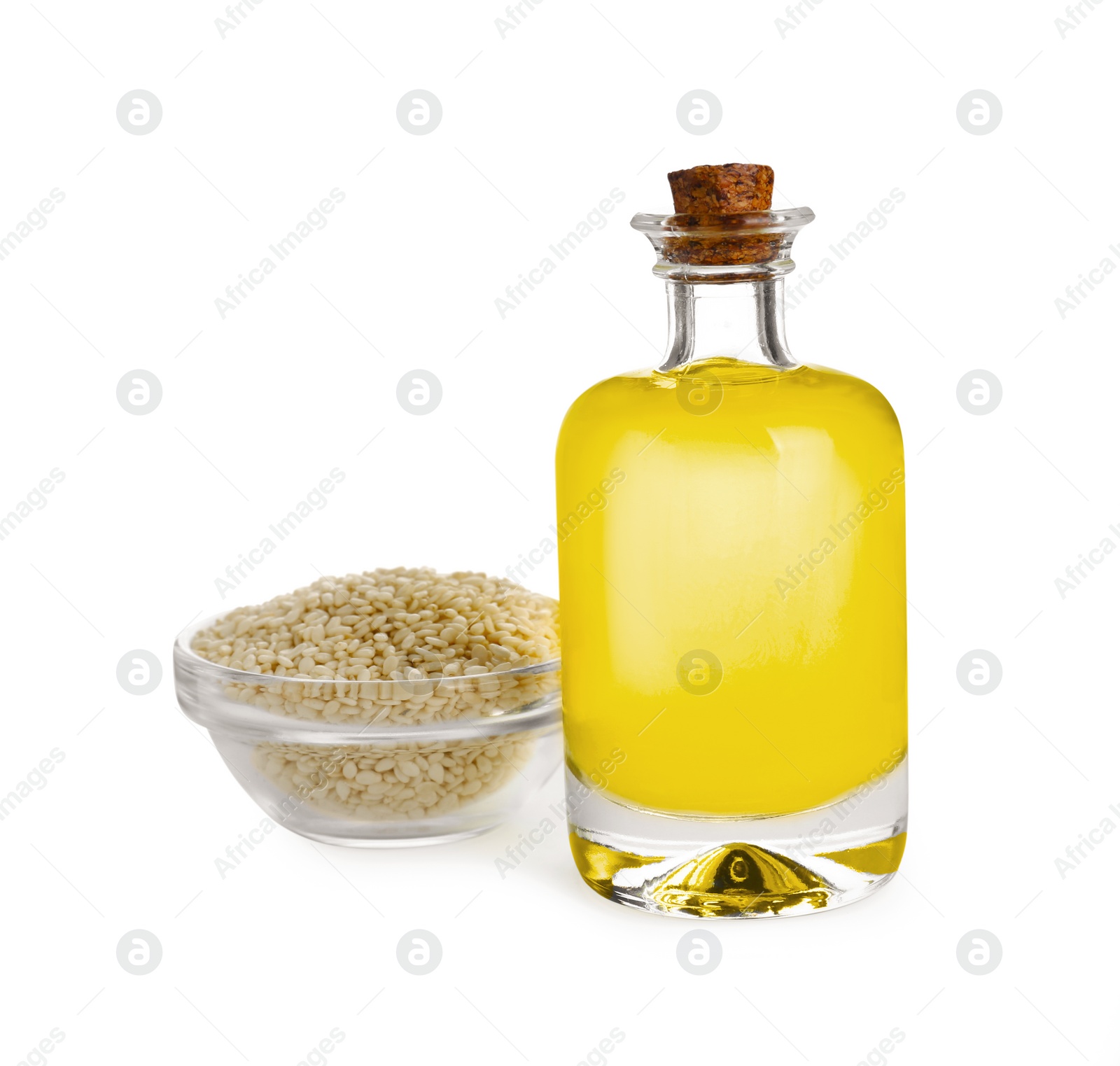 Photo of Glass bottle of fresh sesame oil and bowl with seeds isolated on white