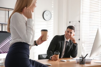 Photo of Man flirting with his colleague during coffee break in office
