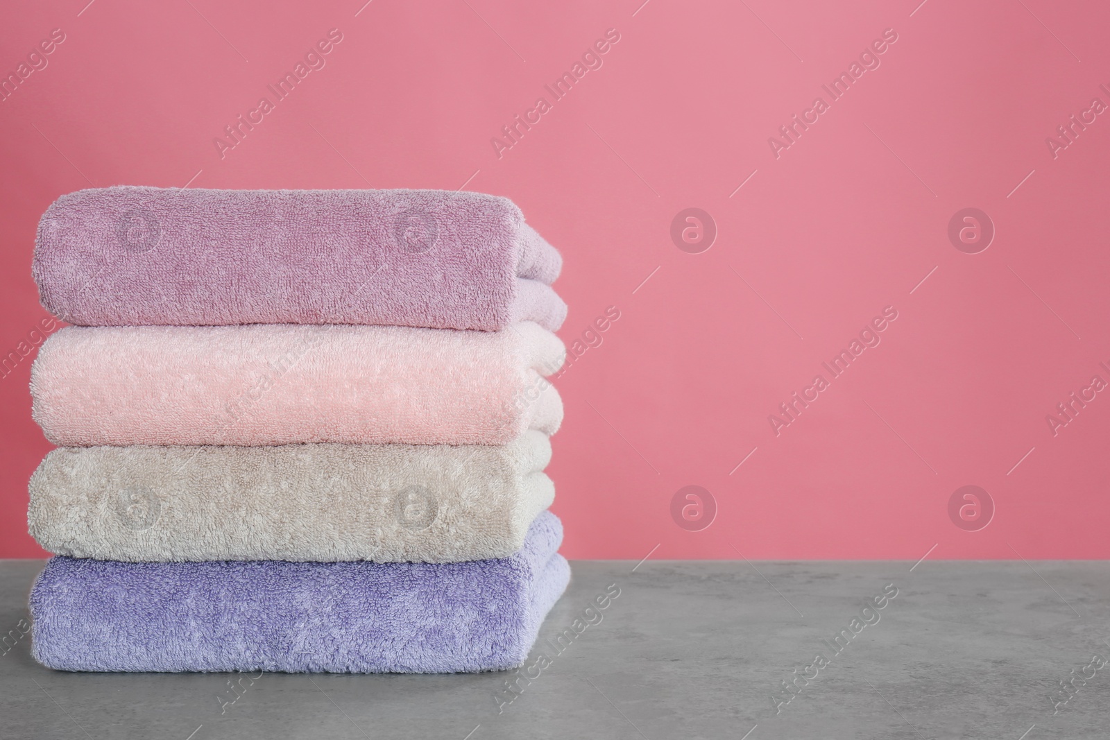 Photo of Stack of color towels on light grey stone table. Space for text