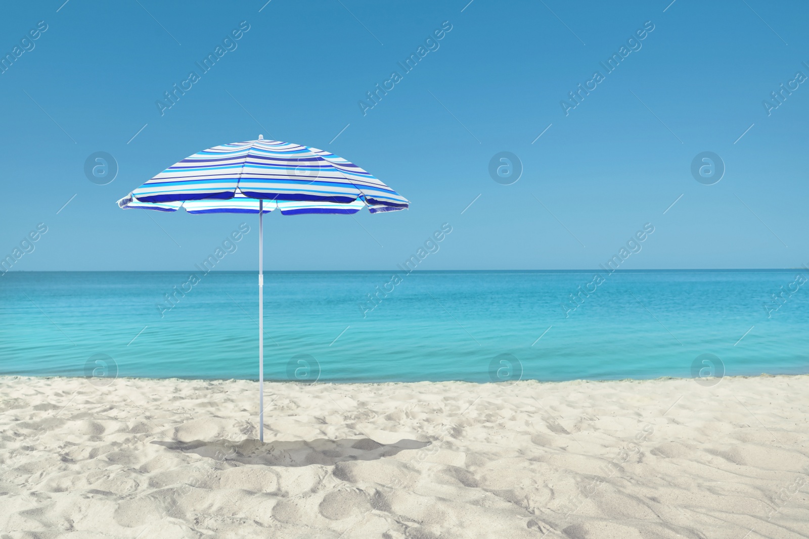 Image of Open big beach umbrella on sandy coast 