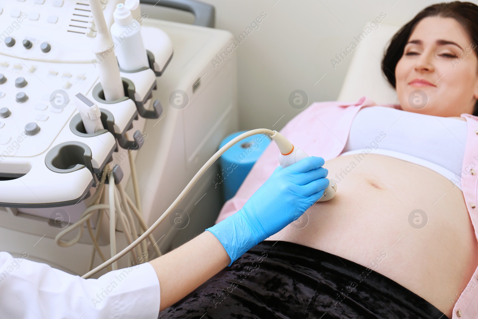 Photo of Young pregnant woman undergoing ultrasound scan in clinic