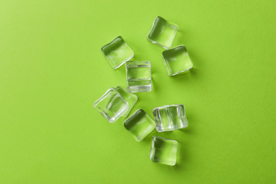 Photo of Crystal clear ice cubes on green background, flat lay