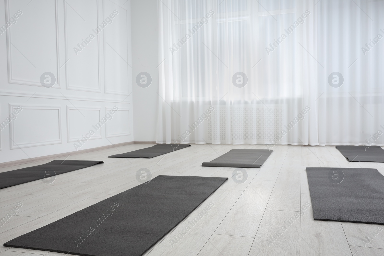 Photo of Spacious yoga studio with exercise mats. Space for text