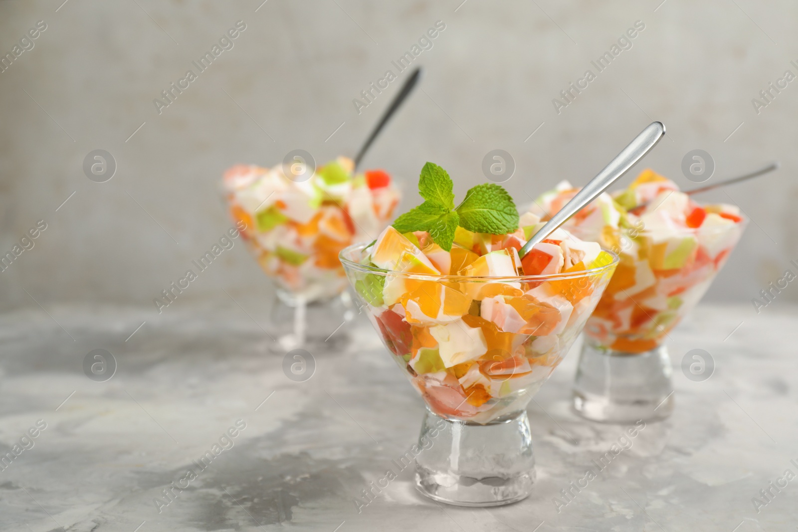 Photo of Delicious broken glass jelly dessert on white marble table, space for text