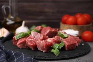 Cut fresh beef meat with basil and spices on brown table, closeup
