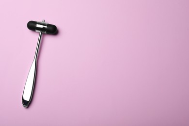 Photo of Reflex hammer on pink background, top view with space for text. Nervous system diagnostic