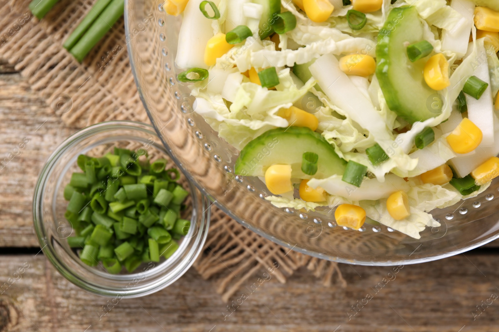 Photo of Tasty salad with Chinese cabbage, corn and cucumber in bowl on wooden table, flat lay