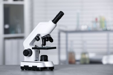 Photo of Modern medical microscope on grey table in laboratory, space for text