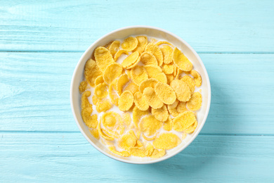Tasty crispy corn flakes with milk on light blue wooden  table, top view