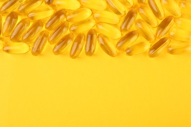 Photo of Many vitamin capsules on yellow background, top view. Space for text