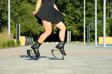 Woman doing exercises in kangoo jumping boots outdoors, closeup