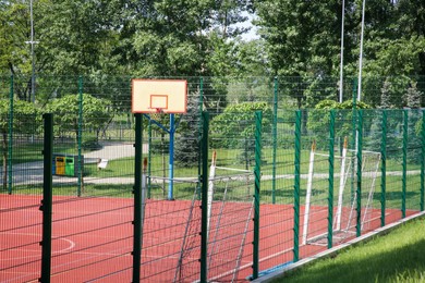 Multi-sport game court with basketball backboard and football goals on sunny day