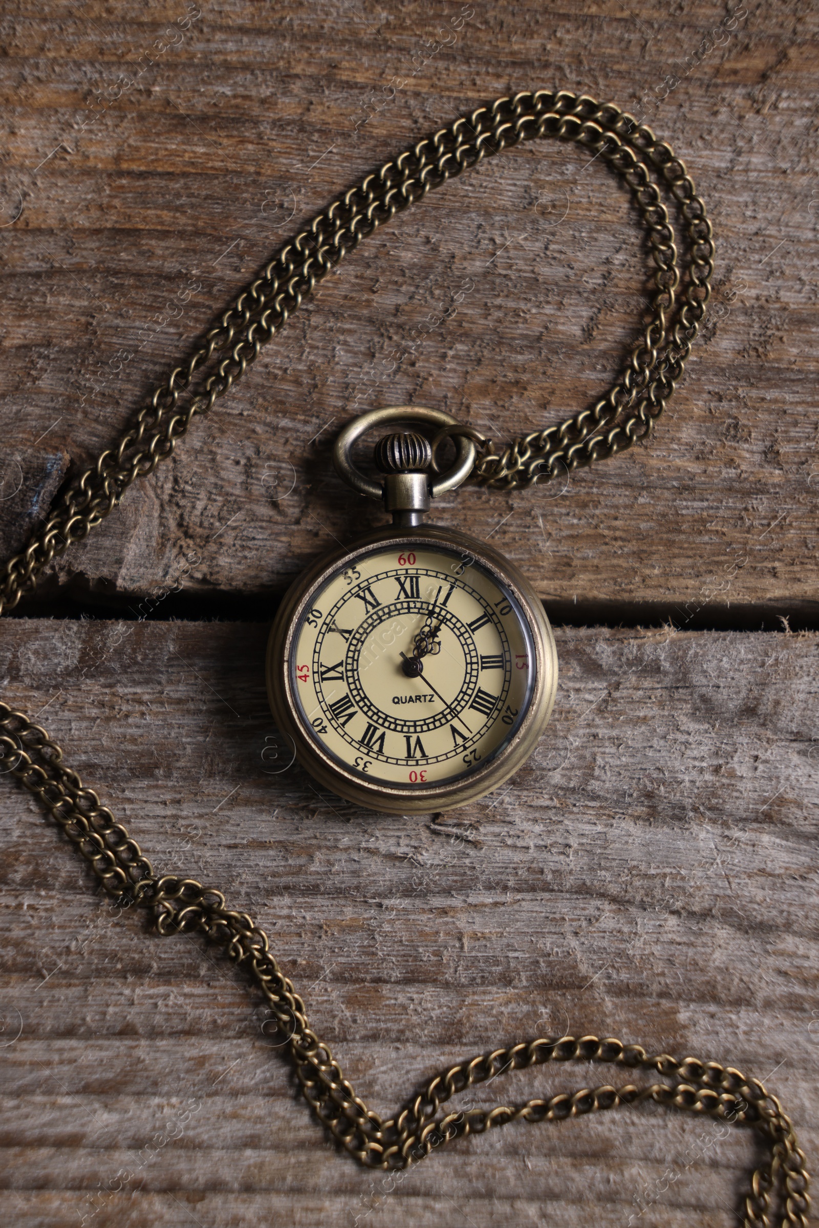 Photo of Pocket clock with chain on wooden table, top view