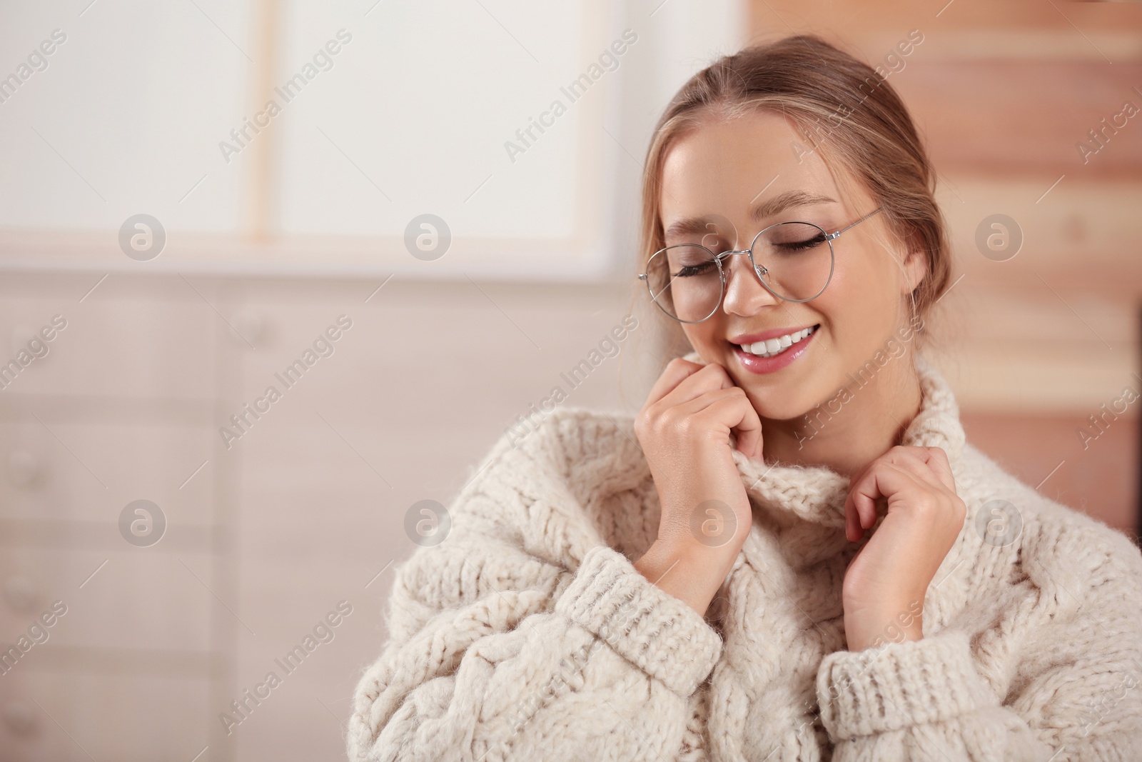 Photo of Beautiful young woman in warm sweater at home, space for text. Winter season