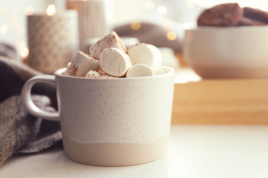Photo of Cup of delicious hot cocoa with marshmallows on white table, closeup. Winter drink