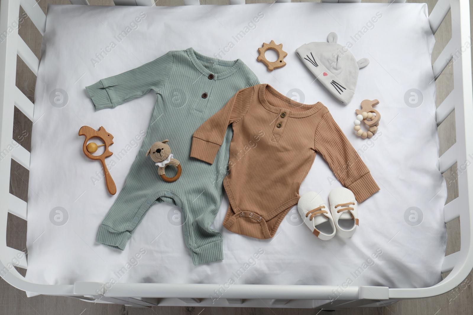 Photo of Flat lay composition with cute baby clothes and accessories on white bedsheet in crib