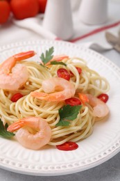 Tasty spaghetti with shrimps, chili pepper and parsley on grey table, closeup