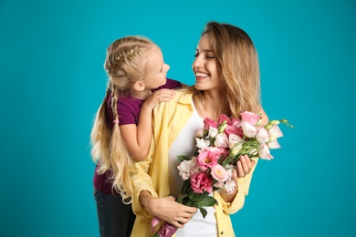 Photo of Little daughter congratulating her mom on blue background. Happy Mother's Day
