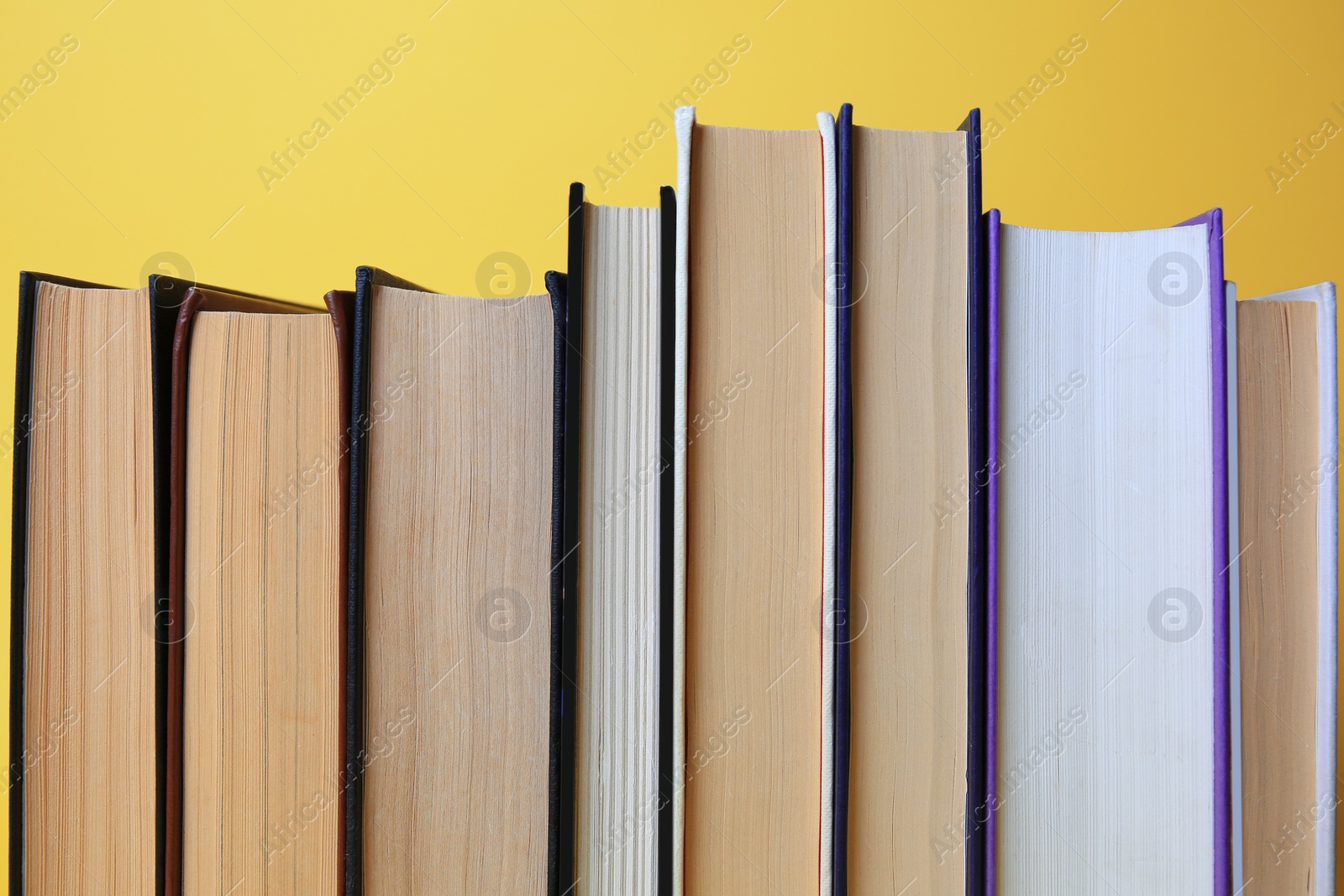 Photo of Collection of hardcover books on yellow background, closeup