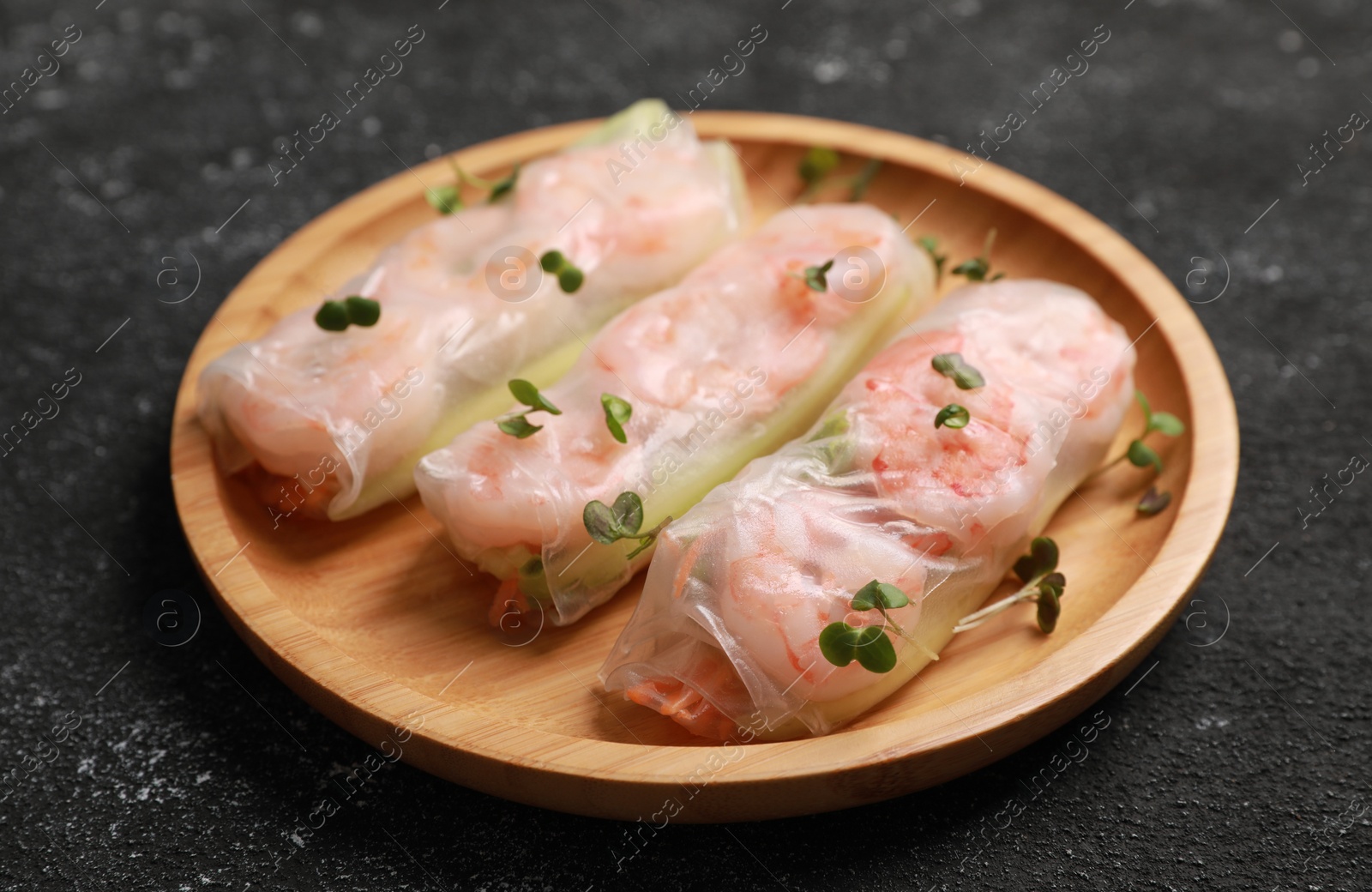 Photo of Plate with tasty spring rolls and microgreens on grey textured table, closeup