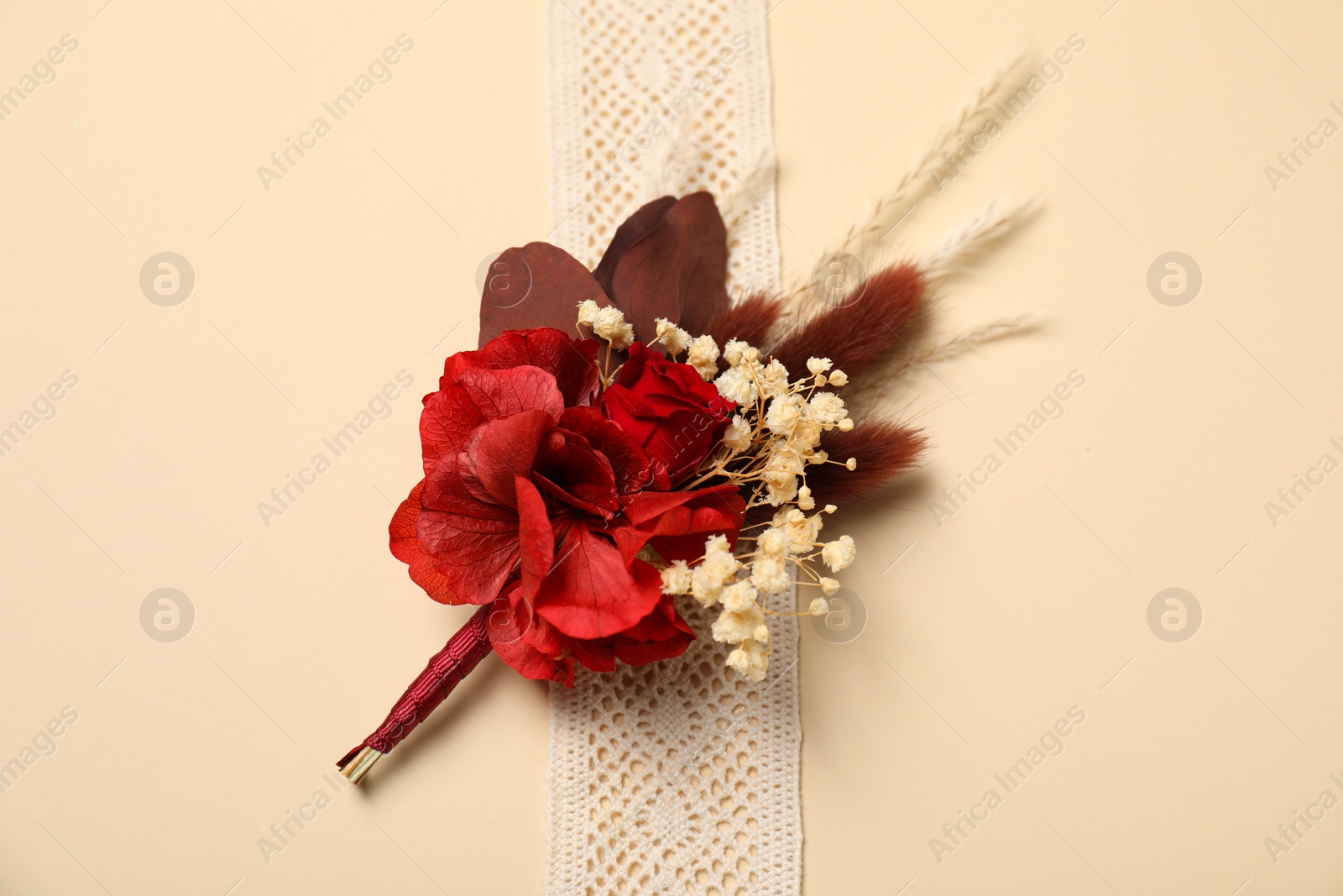 Photo of Stylish red boutonniere and ribbon on beige background, top view