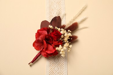 Stylish red boutonniere and ribbon on beige background, top view