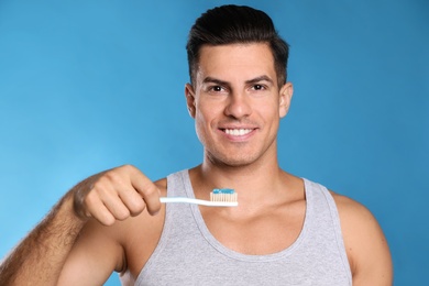 Photo of Man holding toothbrush with paste on blue background