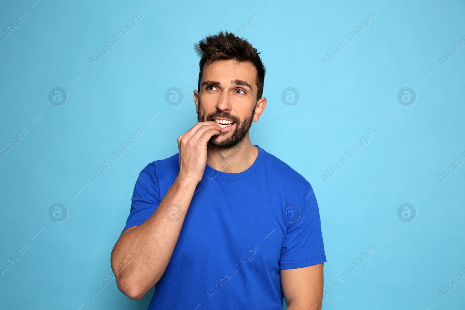 Photo of Man biting his nails on light blue background