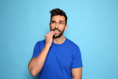 Photo of Man biting his nails on light blue background