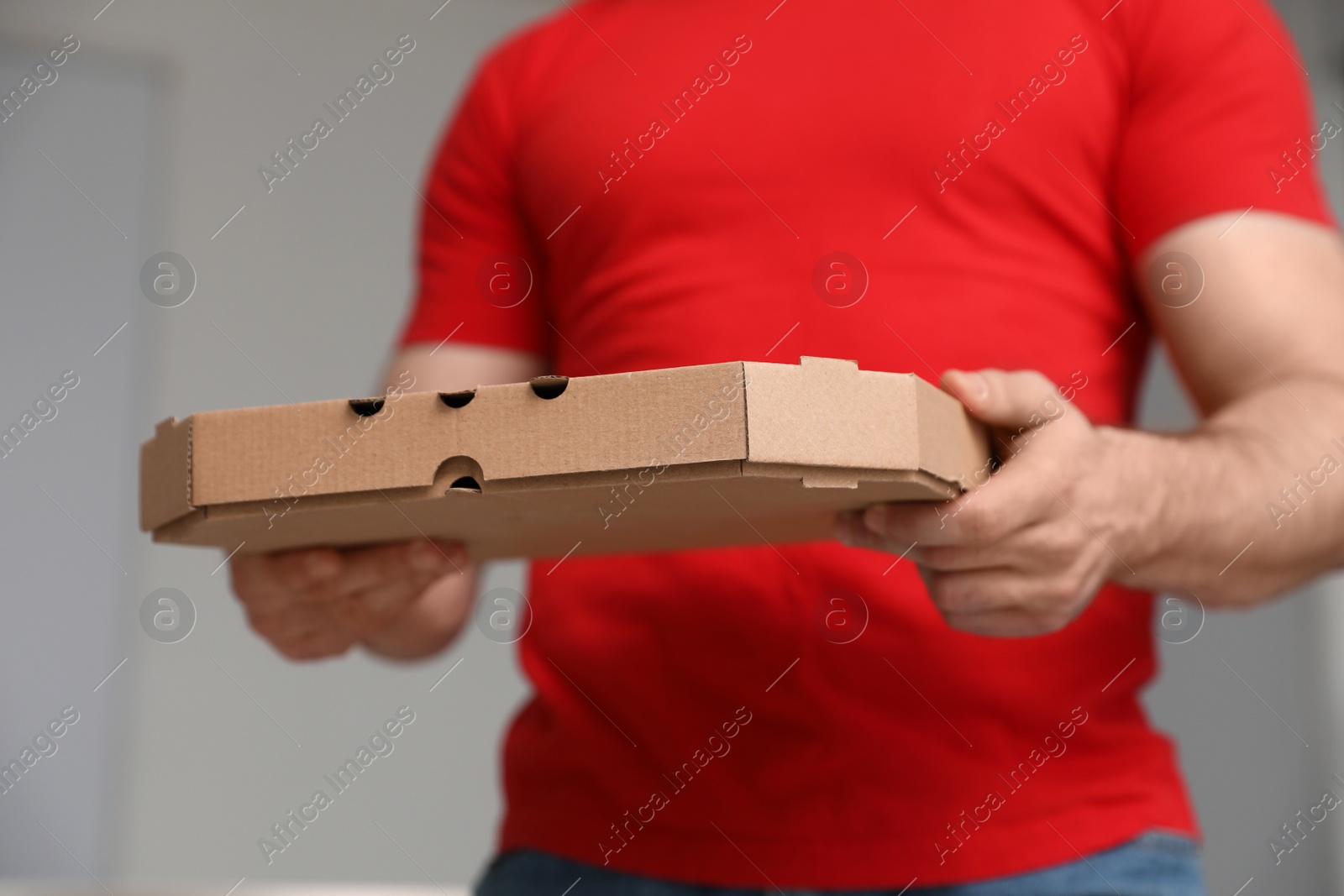 Photo of Courier with pizza box on blurred background, closeup