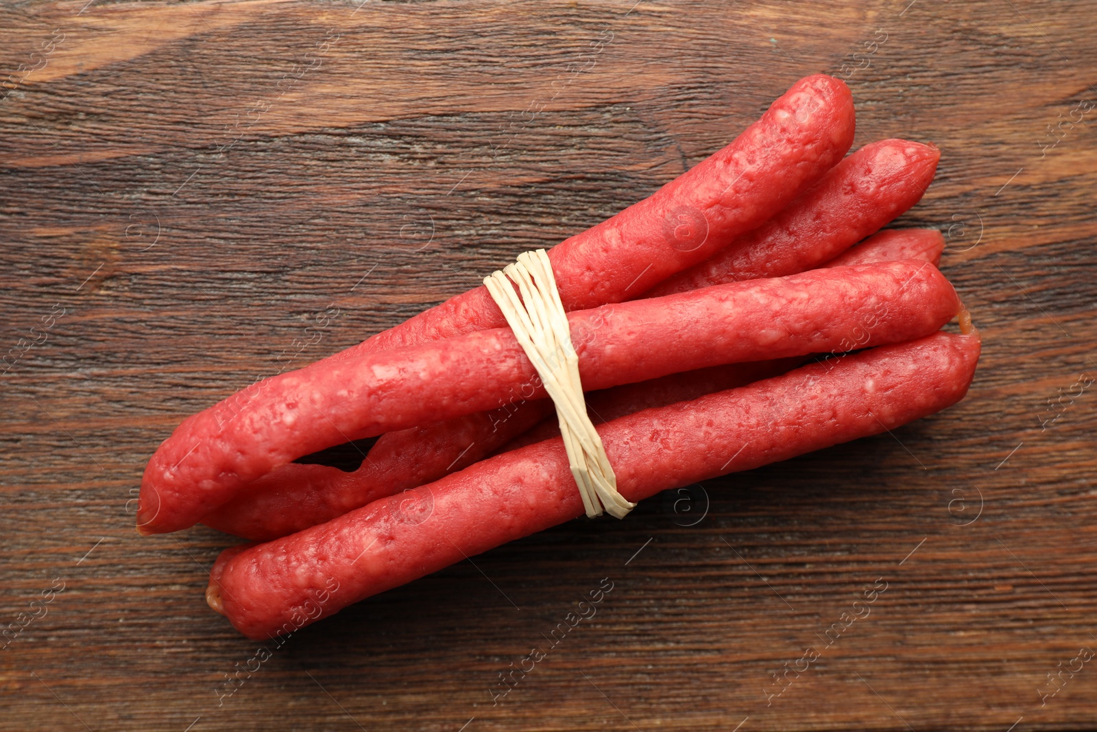 Photo of Many thin dry smoked sausages on wooden table, top view