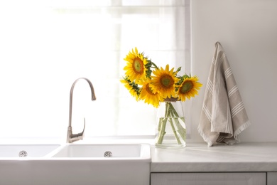 Vase with beautiful yellow sunflowers in kitchen