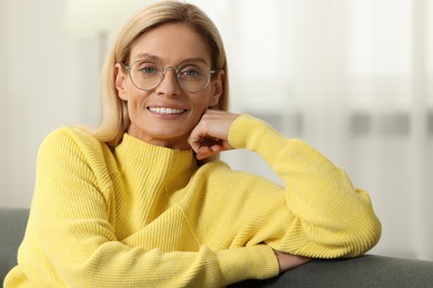 Happy woman in stylish glasses on sofa indoors