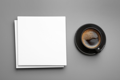 Photo of Blank paper sheets for brochure and cup of coffee on grey background, flat lay. Mock up