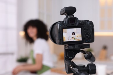 Photo of Food blogger recording video in kitchen, focus on camera